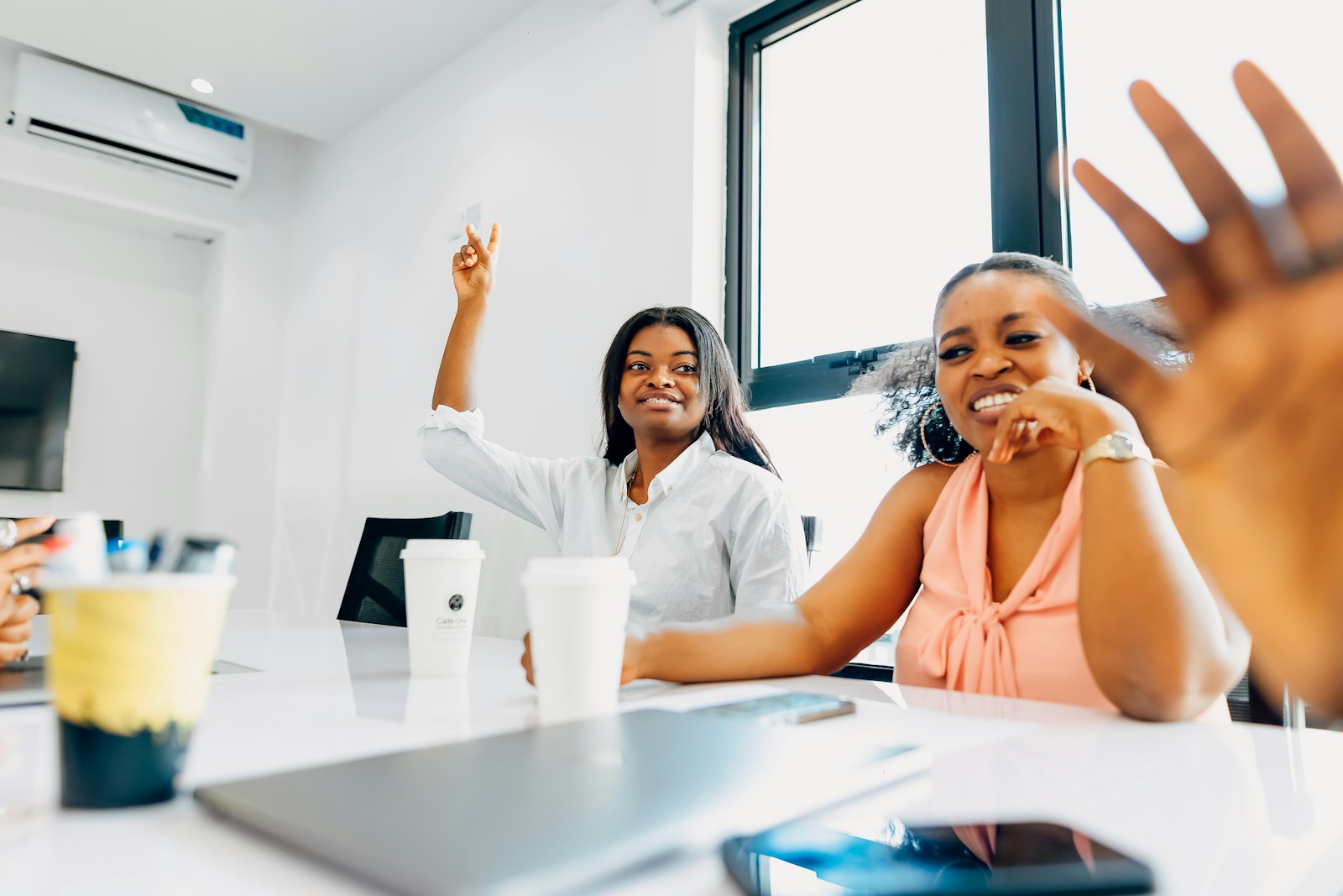 Colleagues smiling and raising their hands during a team meeting